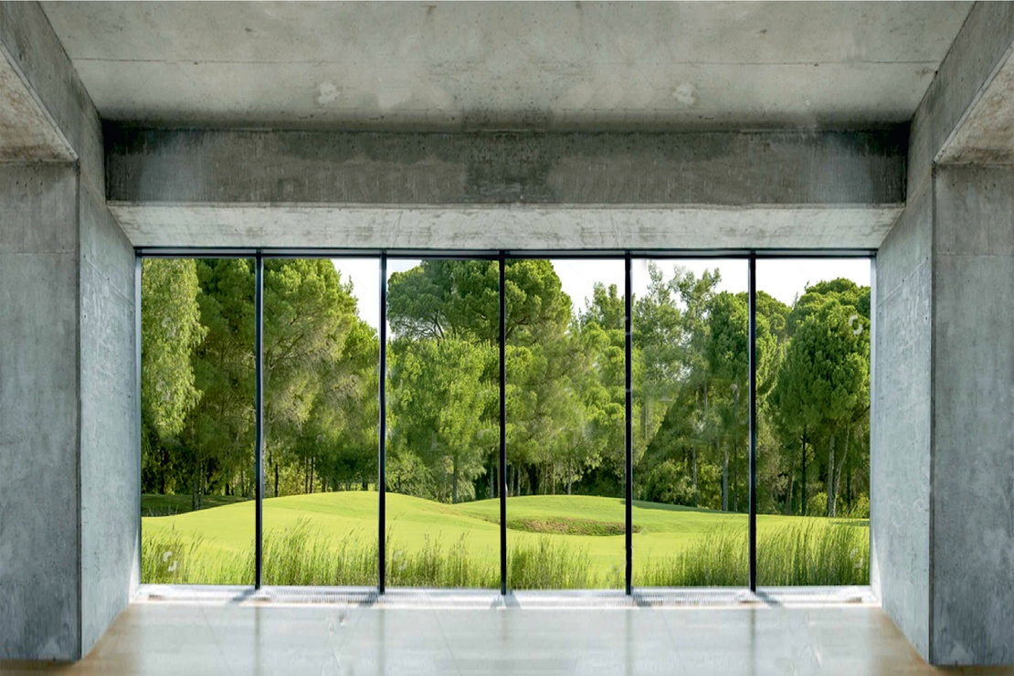 Betonfassade von innen, große Fenster mit Blick ins Grüne