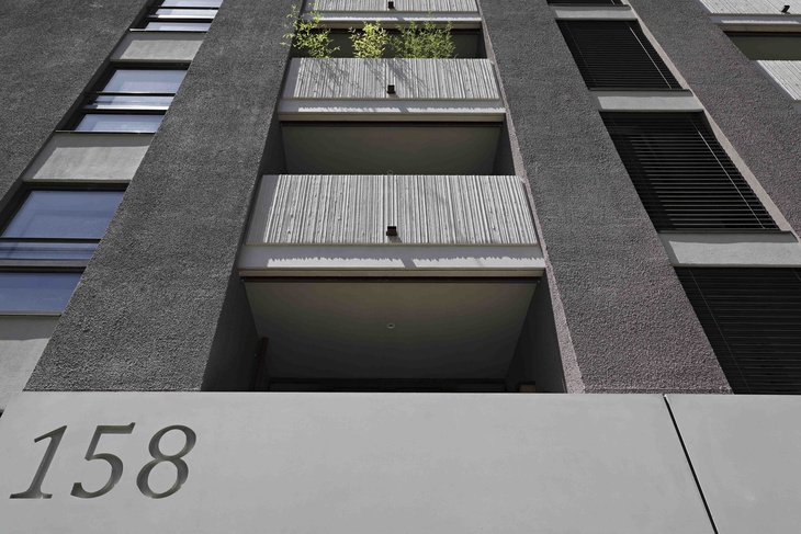 Eingangsdetail mit Hausnummer der grauen Sichtbetonfassade mit unterschiedlicher Oberflächenbeschaffenheit