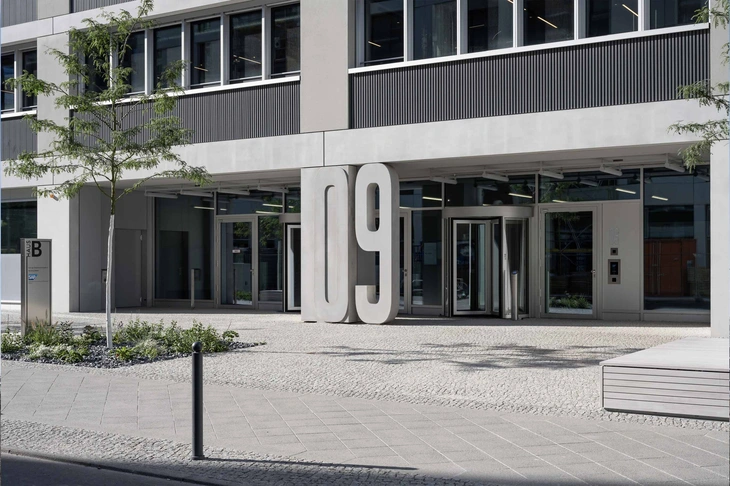 Eingang QH-Track Berlin mit einer grauen Sichtbetonfassade